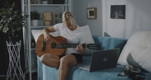 girl learning guitar via laptop