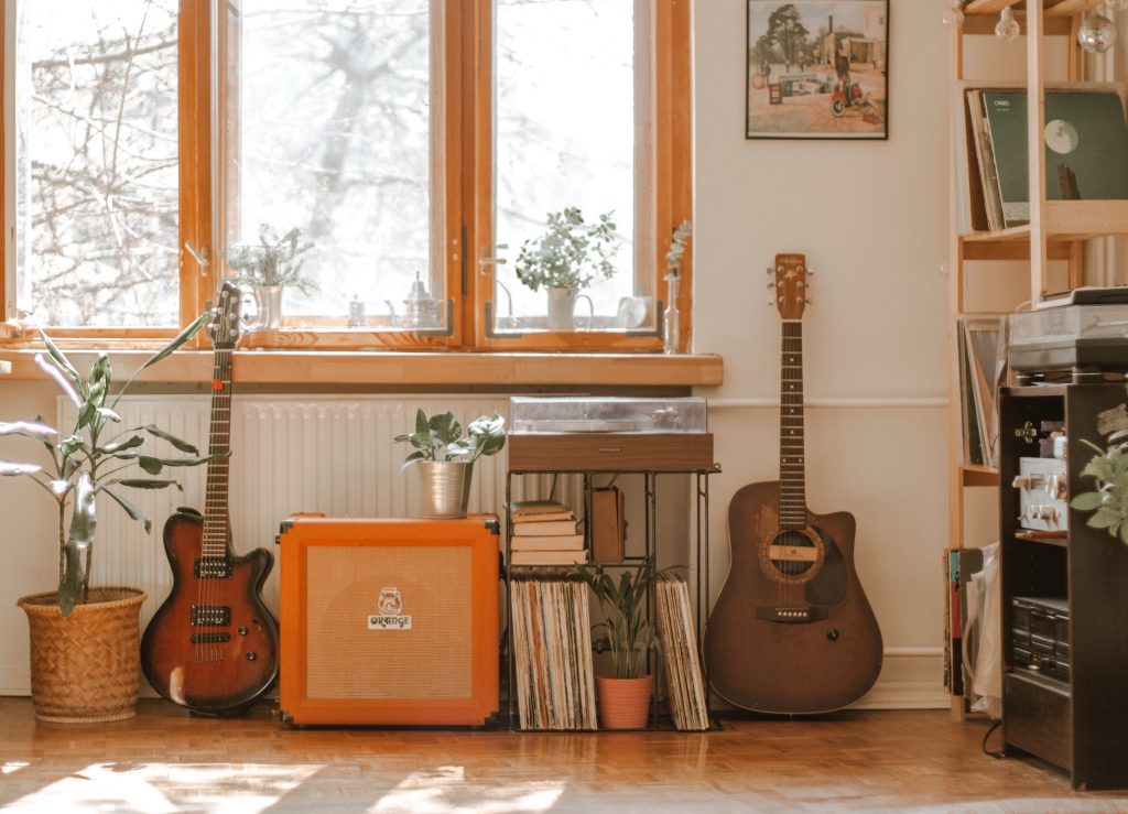 A room with two guitars, amps, and record players with vinyls
